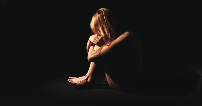 Naked woman with separation anxiety disorder in dark. Scared victim.