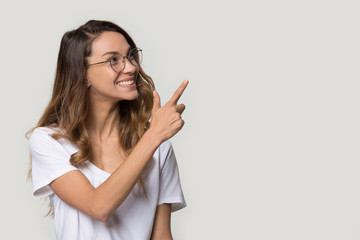 Naklejka premium Happy woman in glasses pointing finger at copy space