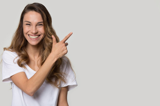 Laughing woman pose over white grey background pointing at copyspace
