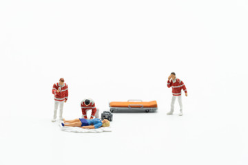 Miniature people, emergency medical team with unconcious  patient and pills on the ground. Concept of health care, emergency, life insurance, accident background