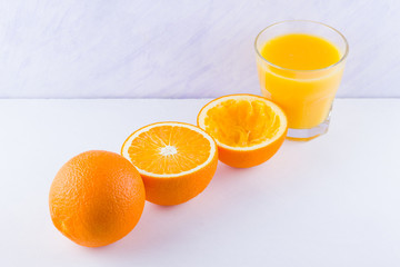 Orange fruits with juice, concept. Orange juice and halves of oranges on white background. Citrus for making juice. Whole and squeezed oranges and glass of juice