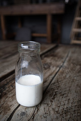 Miniature milk bottle with milk inside on a dark wood rustic table