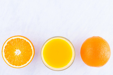 Orange fruits with juice, concept. Orange juice and halves of oranges on white background. Citrus for making juice. Whole and squeezed oranges and glass of juice