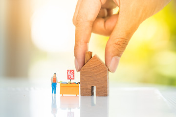 Woman's hand picking house model and display shelf with shopper. Concept for property ladder, mortgage and real estate investment .