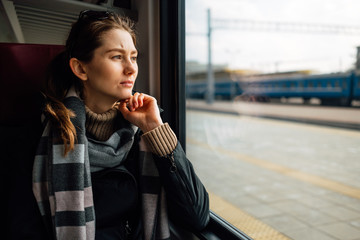 Young woman traveling looking out the window while sitting in the train
