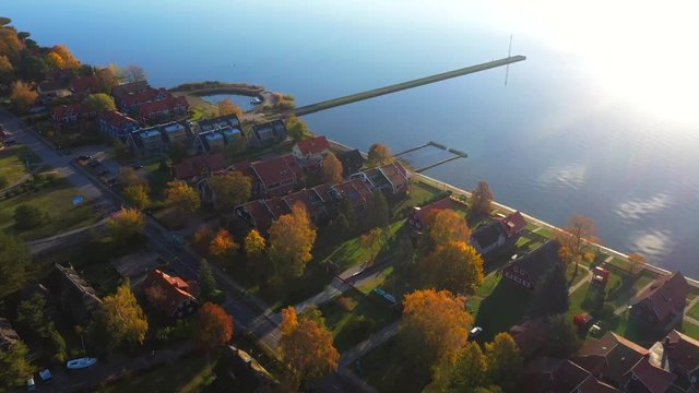 Panoramic drone shot of Pervalka, small village in Lithuania, near the coastline and the calm sea, reflecting white clouds on the surface, on a bright sunny day