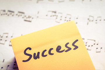 Motivation concept. Message on a sticky paper with music scores on the background. Success concept