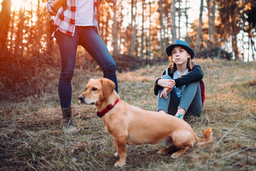 Mother and daughter with dog in forest during sunset