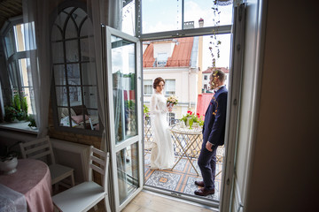 loving couple of newlyweds stand on balcony of old city in summer sunny day