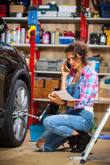 Obraz premium car mechanic woman in blue overalls talking on the phone near a car