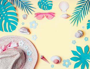 Summer background. Beach accessories with  shells and tropical leaves on light yellow background, top view. Straw hat and sunglasses. Summer holiday vacation. Female fashion outfit . Flat lay