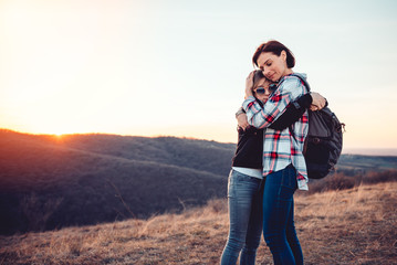 Affectionate mother and daughter hugging on a mountain peak