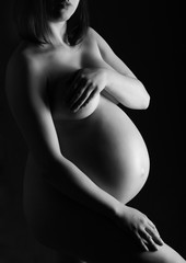 pregnant woman, expectant mother on black background, monoshrome shoot.