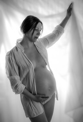 pregnant woman, expectant mother on white background, close-up of pregnant belly, monoshrome shoot.