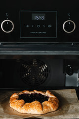 Closeup photo of galette with black currant baking in a oven