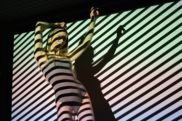 Fototapeta na wymiar Beautiful girl blonde in lingerie dances in black and white stripes from the projector