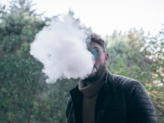 Men with beard vaping outdoor in sunglasses