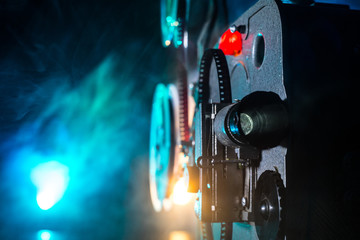 Old vintage movie projector on a dark background with fog and light. Concept of film-making.