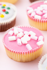 Colorful cupcakes on a pink background.