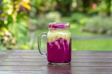 Fresh tropical smoothie with red dragon fruit, green avocado, yogurt and honey in glass mug for breakfast , close up. The concept of healthy eating, superfood . Bali, Indonesia