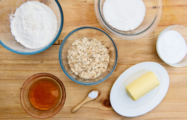 Ingredients for Anzac biscuits a traditional Australian cookies made with flour, rolled oats, desiccated coconut, sugar, butter, baking soda, golden syrup and water, flat lay