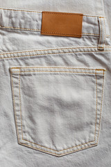 White denim fabric with a back pocket as a background.