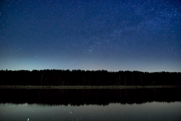 Wonderful beautiful night sky full of stars with Milky way over the river and forest in transparent...