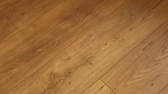 The camera moves along the floor, covered with laminated parquet with a brown wooden texture