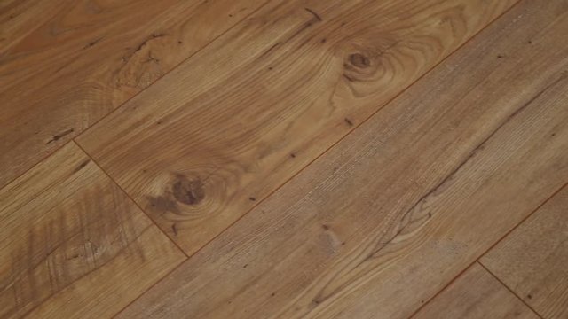 The camera moves along the floor, covered with laminated parquet with a brown wooden texture