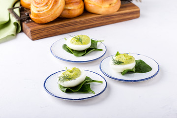 Deviled eggs with avocado and spinach and roll buns on festive Easter table