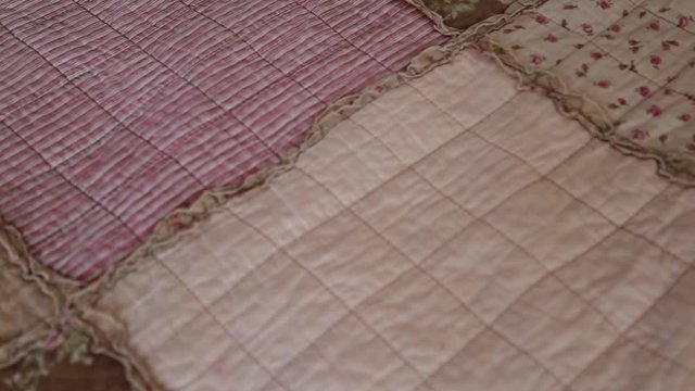 camera moves along beige patchwork quilt closeup.