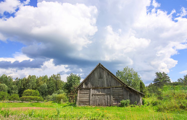 Summer landscape in Latvia, East Europe. Old wooden shed building