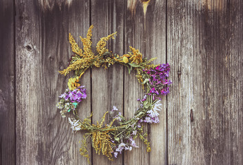 Wreath of wild flowers on the old wooden door background.