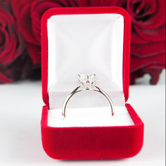 Wedding ring in a cool velvet box against a background of roses