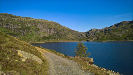 Fototapeta na wymiar Path leads to mountain lake with blue water