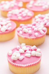 Colorful cupcakes on a pink background.