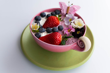 Vegan pink and white Chia pudding in a pink bowl with fresh fruits and flowers