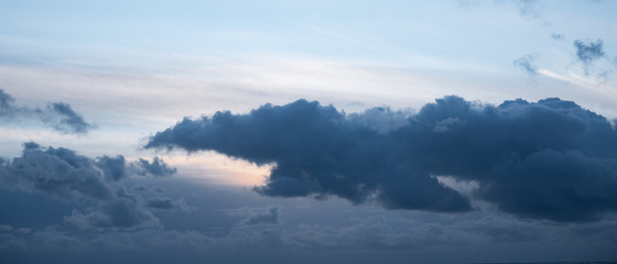 Naklejka na ściany i meble Dramatic, dark grey storm cloud in sky at dusk