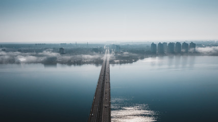 Aerial view of fog or mist over Voronezh river and North Bridge with car traffic, panoramic drone shote from above, morning haze and cityscape
