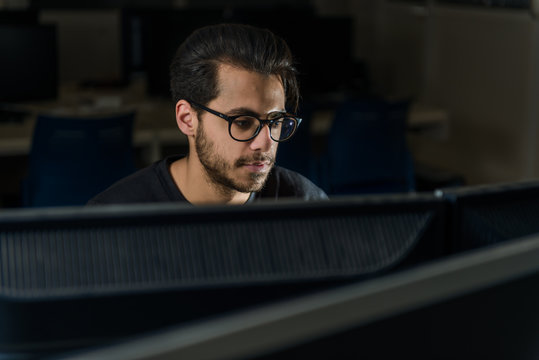 View over a screen of the face of a young computer science student working with the computer.