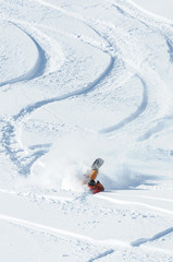 A snowboarder falling into deep snow at the ski resort in a sunny morning