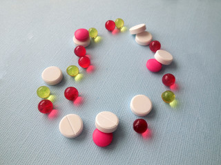 Pharmaceutical and vitamin tablets on a matte blue background texture with a place under the heart-shaped text