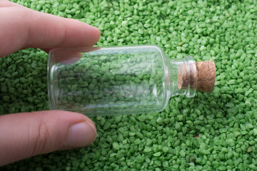 Empty bottle in hand on green sand