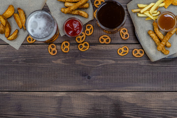 Mix of snacks with beer on dark wooden background. Top view, Empty space for text