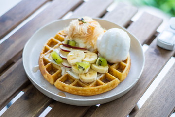 Golden brown waffle topped with ice cream Fruit sliced and whipped cream and Cotton Candy