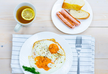 Traditional breakfast -  sausage, fried eggs and bread with hot tea