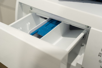 Close-up of the open box for detergents in the washing machine in the white bathroom