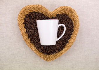 White Cup lying on coffee beans in a straw heart