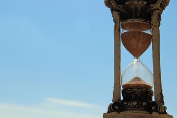 vintage hourglass on blue sky background on a sunny day, copy space to the left. hourglass on the...