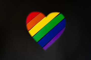 Multi-colored heart (lgbt flag colors) in the center on a blurred black background showing love without boundaries and rules. Top view